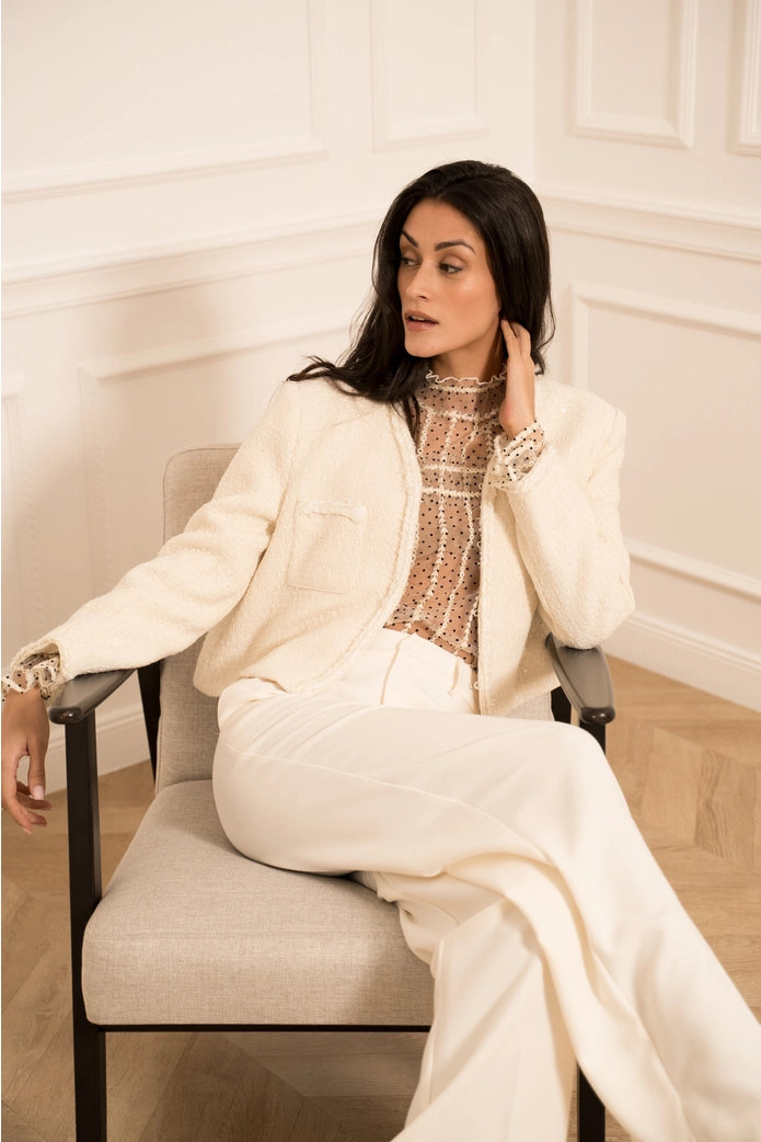 Woman in a white outfit sitting on a chair in a room with white walls.