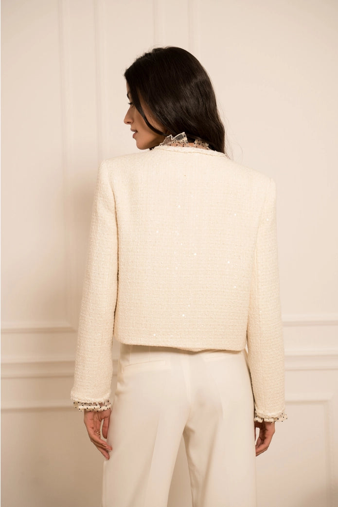 Woman wearing a cream-colored suit against a plain background