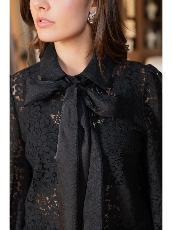 Black lace blouse with a tie detail worn by a person.