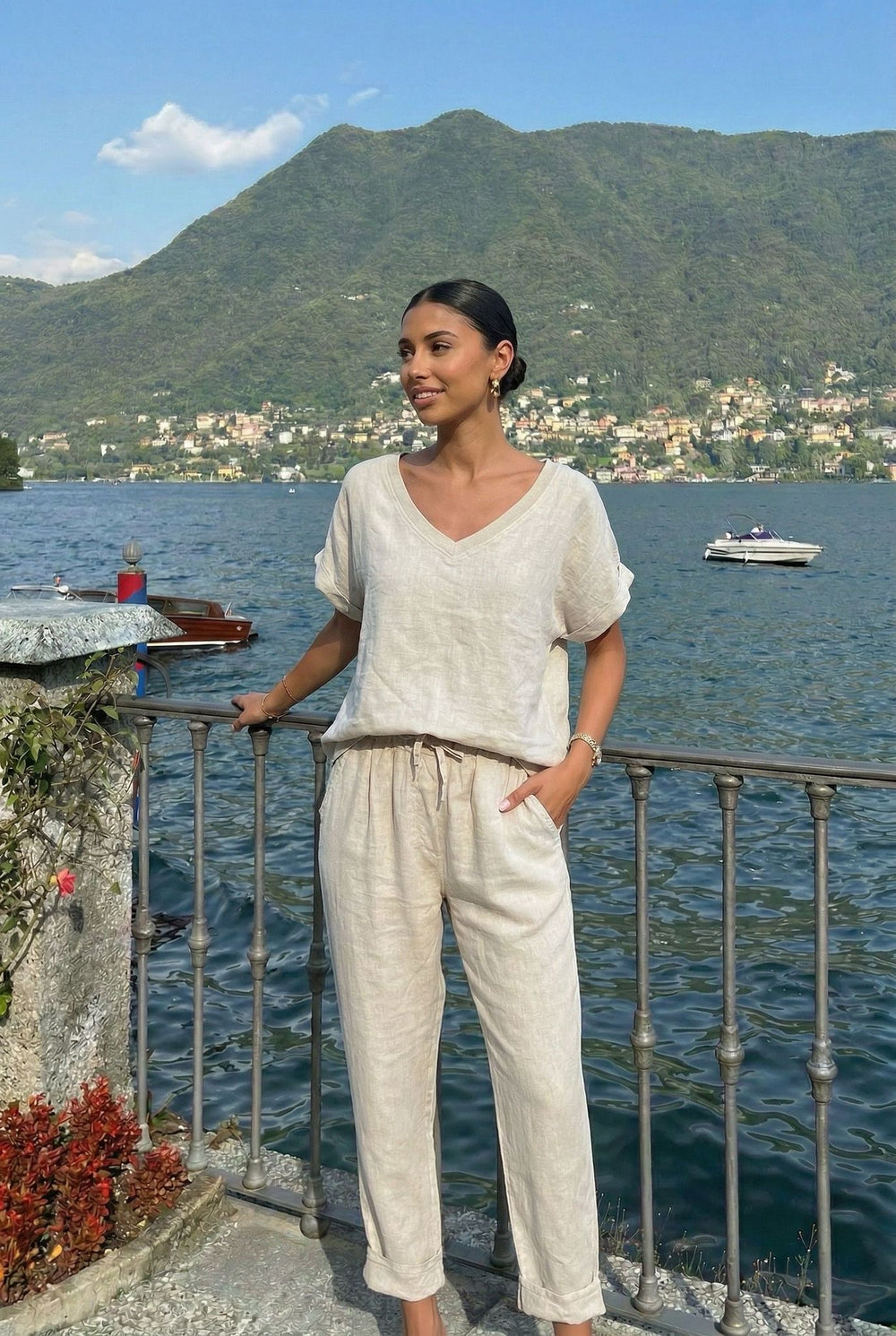 Woman standing by a railing overlooking a lake with mountains in the background