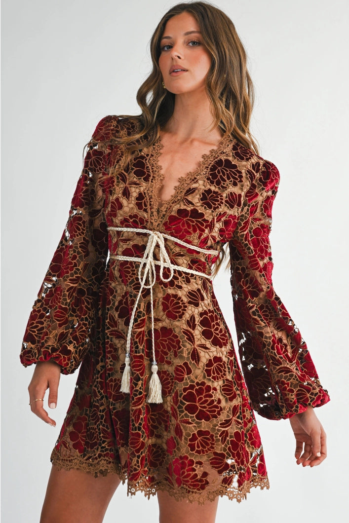 Woman wearing a floral lace dress with long sleeves on a white background