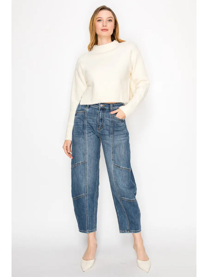 Woman wearing a white sweater and blue jeans on a white background