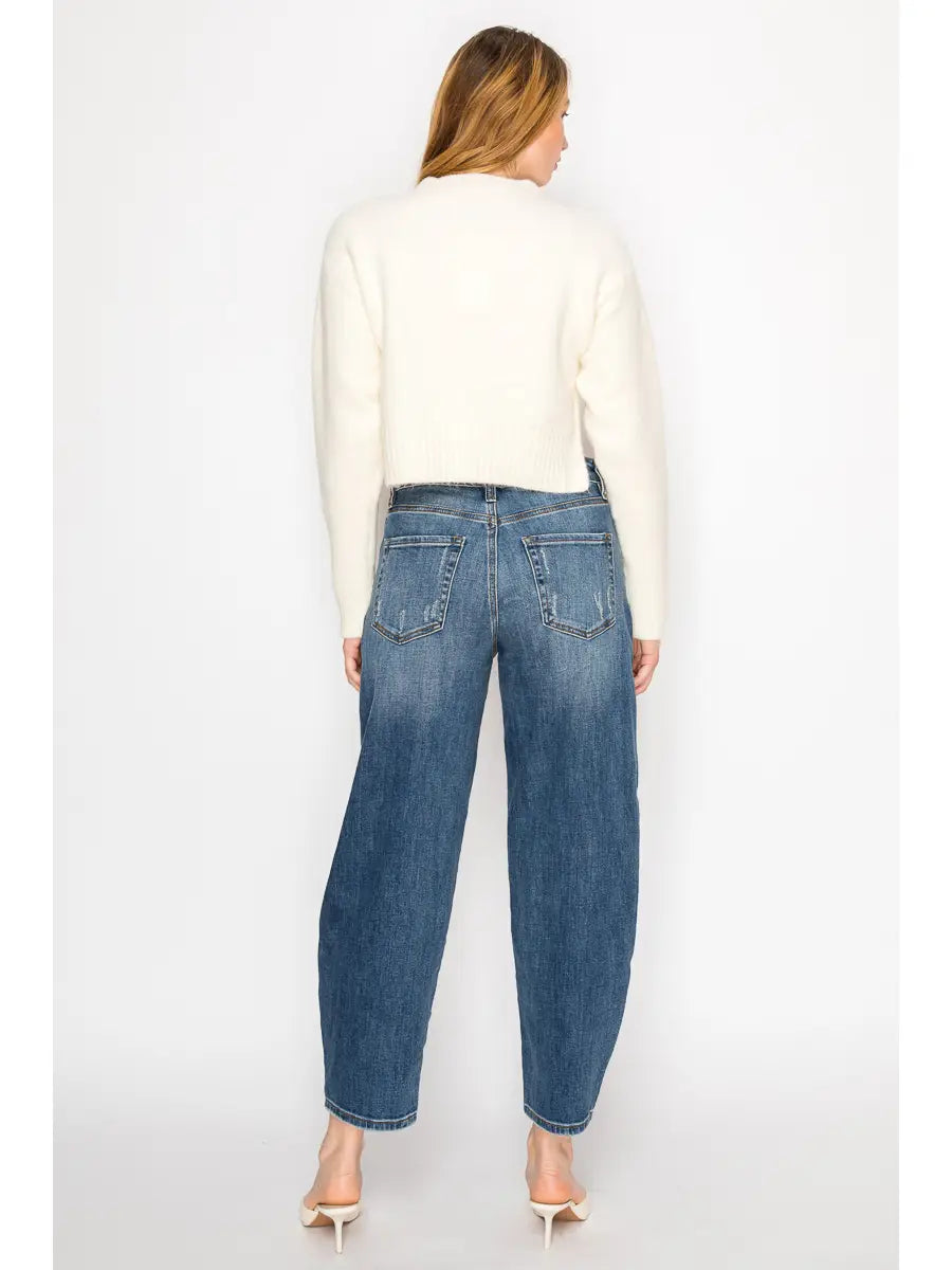 Woman wearing blue jeans and a white sweater on a white background