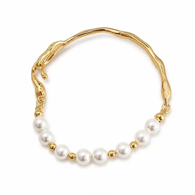 A gold-plated wavy cuff bracelet featuring a row of white freshwater pearls separated by small gold beads, set against a plain white background.