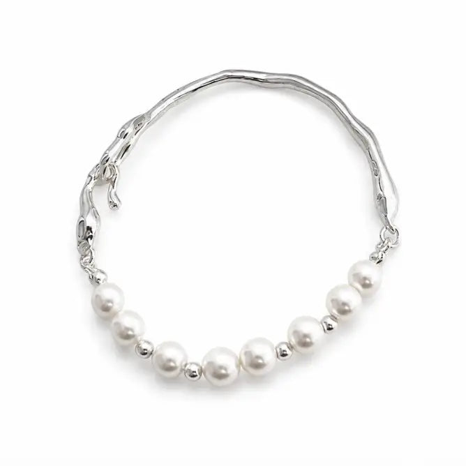 A silver-toned wavy cuff bracelet featuring a row of white freshwater pearls and small silver spacer beads along the front, displayed on a clean white background.