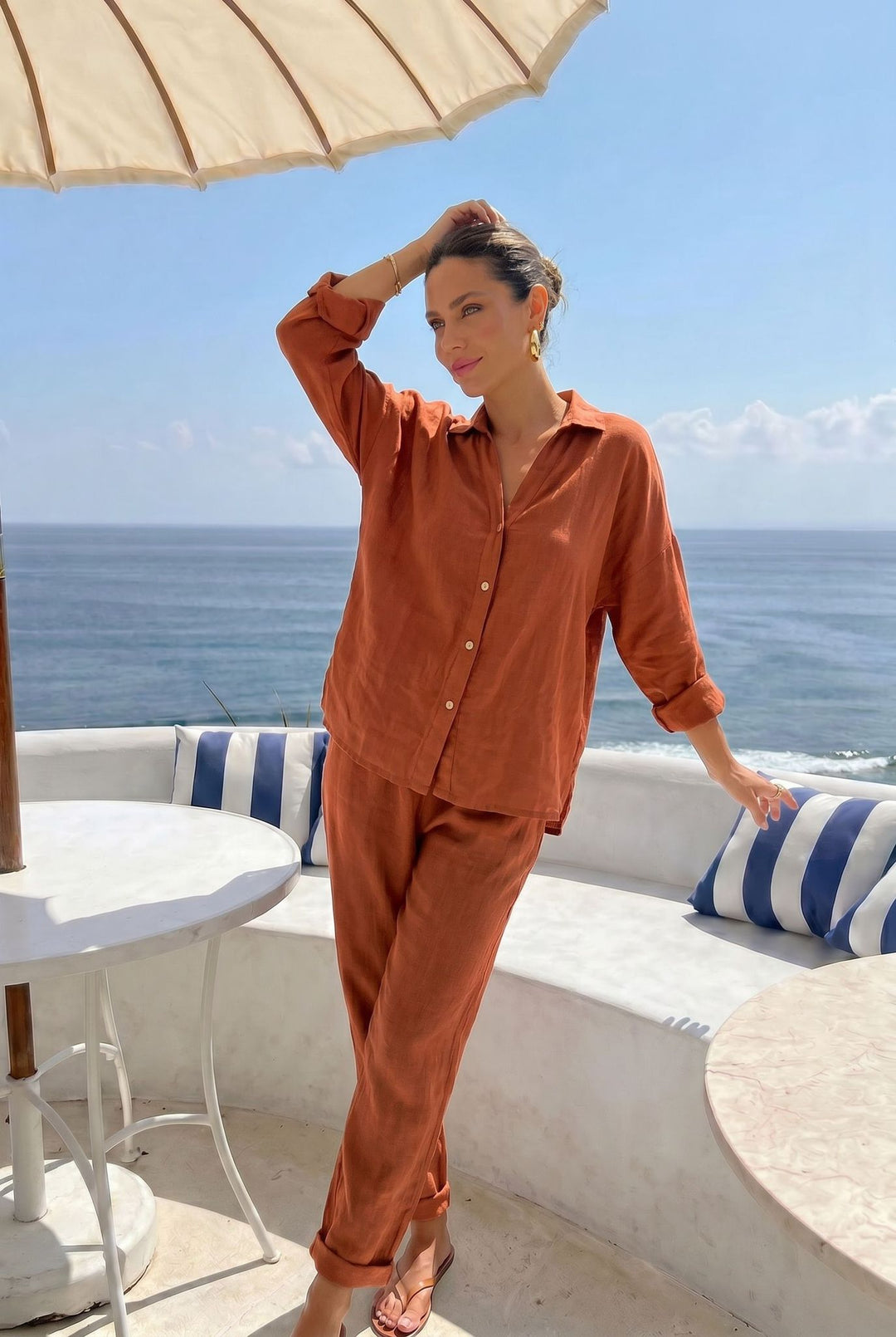Woman in orange outfit standing on a balcony with ocean view