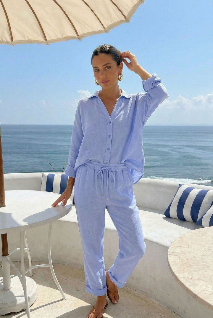 Woman in a light blue outfit standing on a balcony with ocean view
