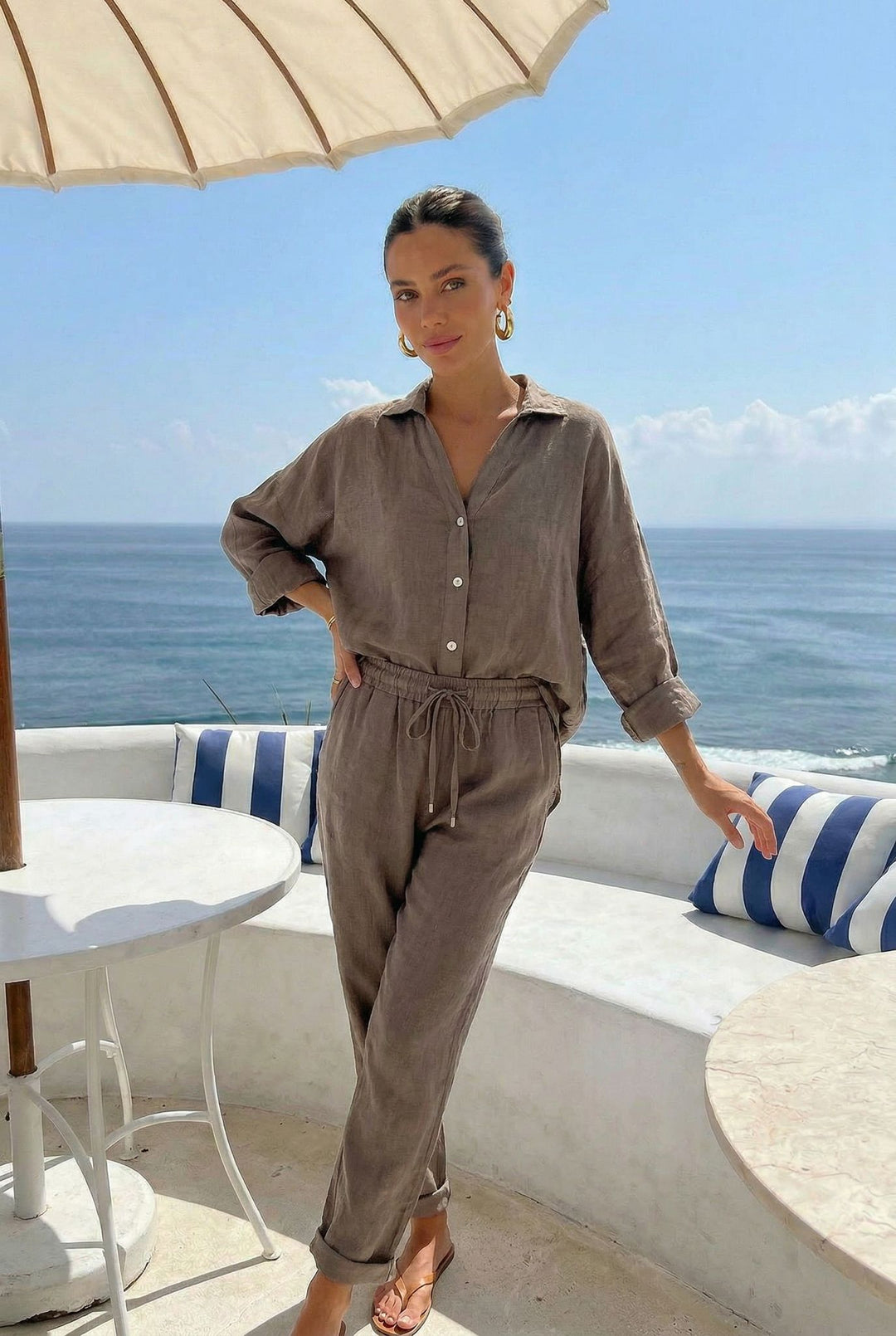 Woman in a brown outfit standing on a balcony with ocean view
