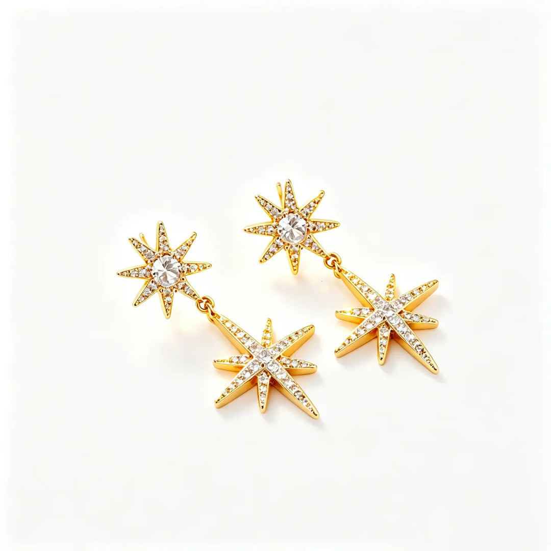 A pair of gold starburst dangle earrings with clear rhinestones, displayed on a clean white background.
