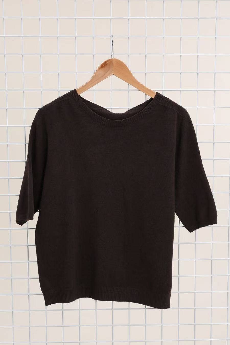 Black sweater on a hanger against a grid background