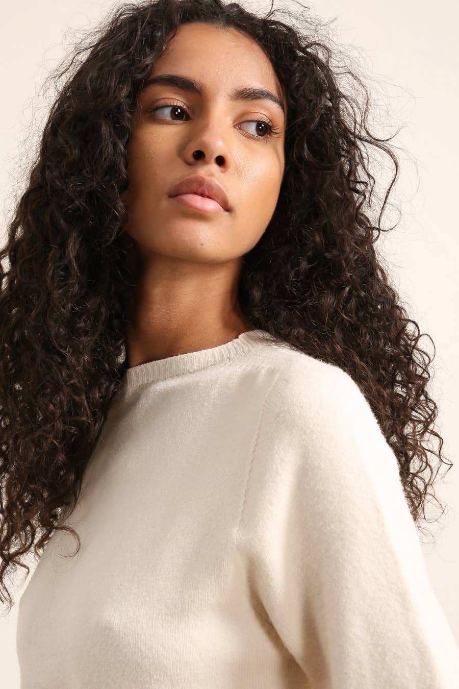 Woman wearing a beige sweater against a plain background