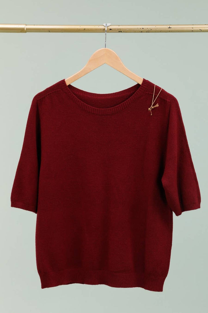 Maroon sweater on a wooden hanger against a light gray background