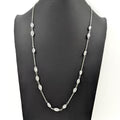 Necklace with black and silver beads on a plain background