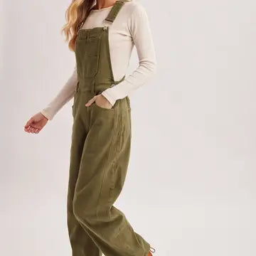 A model wearing olive green wide-leg denim overalls over a cream long-sleeve top, shown from the waist down against a plain light background.