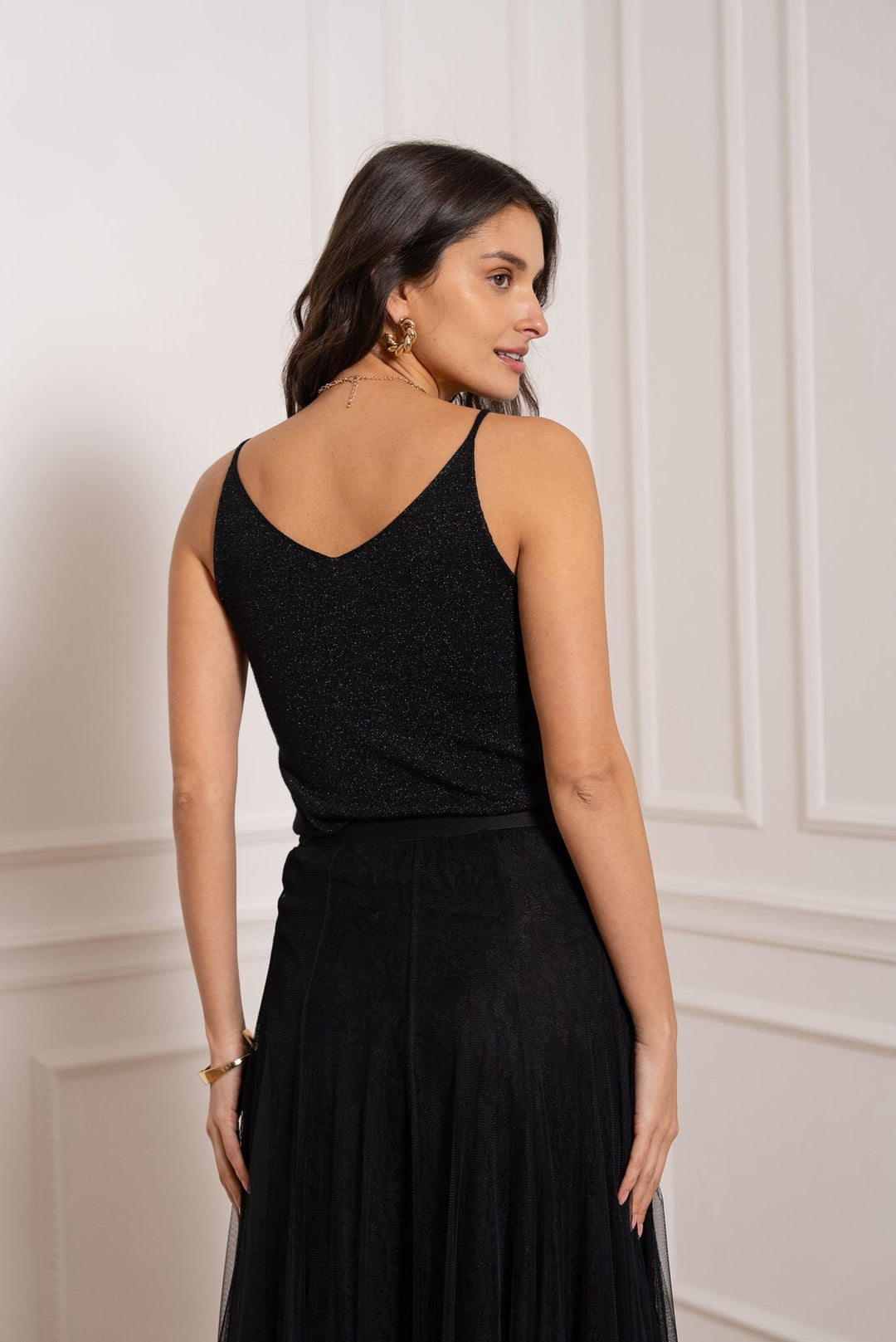 Woman wearing a black dress against a white wall