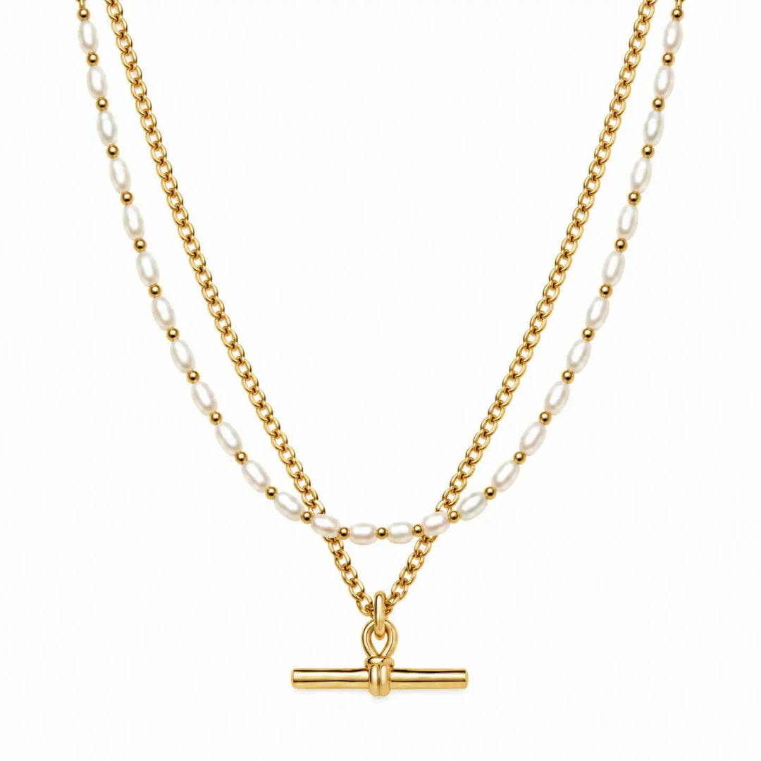 A double-strand necklace featuring a gold chain and a white pearl chain, both adorned with small gold beads and culminating in a polished gold toggle clasp, shown against a plain white background.