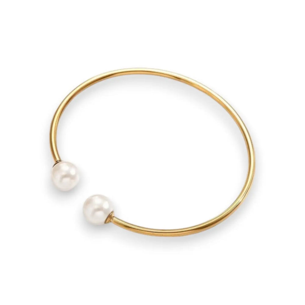 A minimalist gold open cuff bangle bracelet featuring two small, round white pearl beads at the ends, shown on a clean white background.
