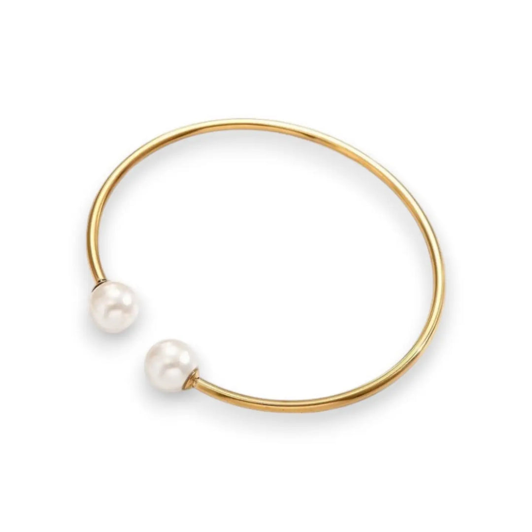 A minimalist gold open cuff bangle bracelet featuring two small, round white pearl beads at the ends, shown on a clean white background.