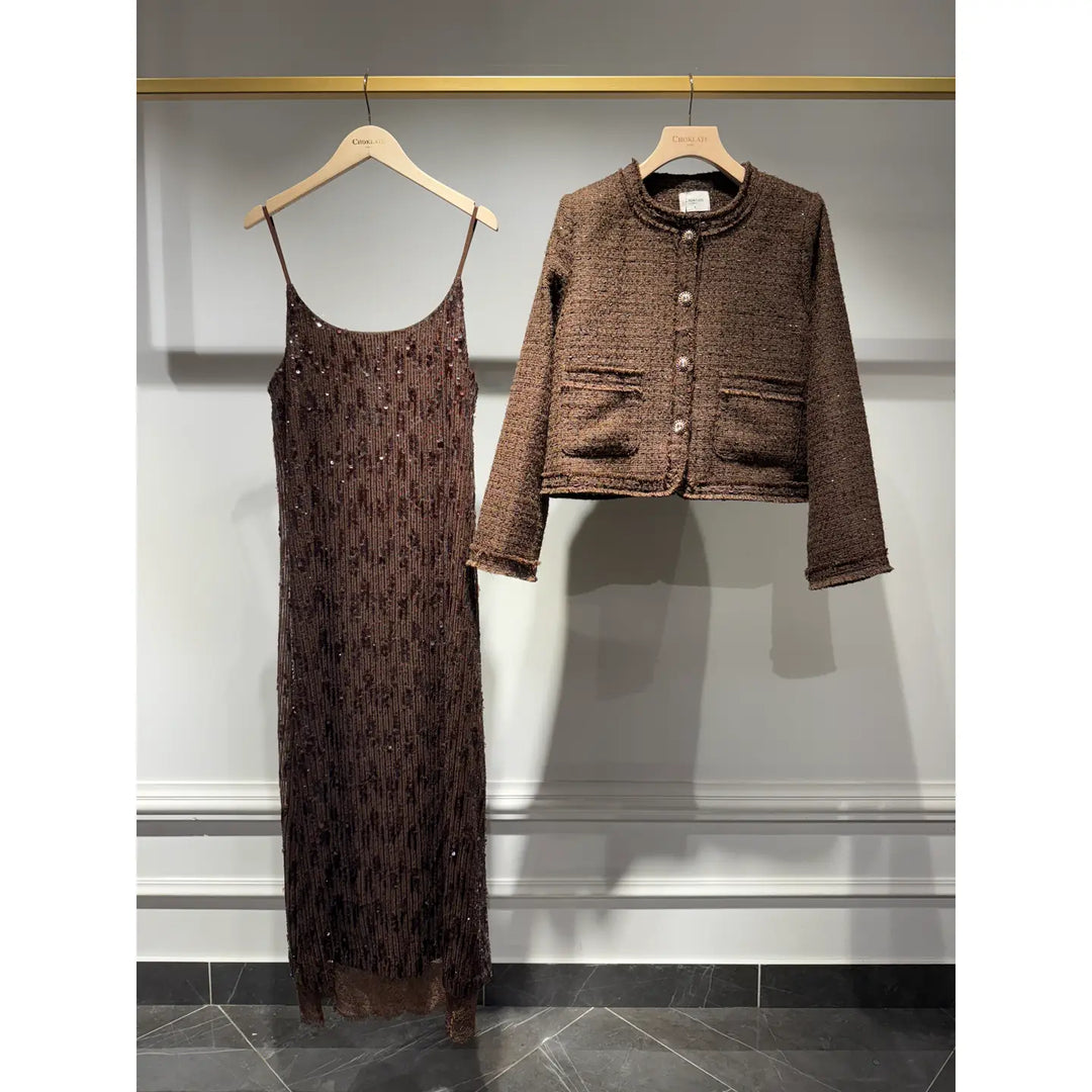 Brown dress and jacket set on hangers against a gray wall.