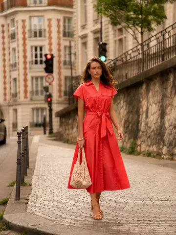 Woman in a red dress walking on a street in an urban setting