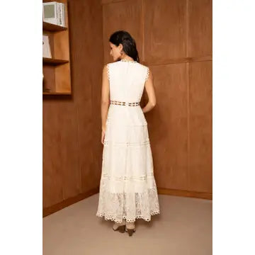 Woman in a white dress standing in a room with wooden walls.