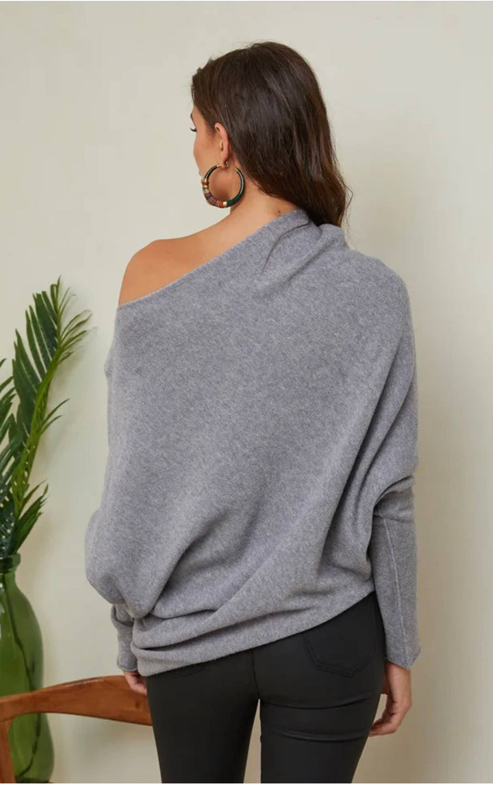 Woman wearing a gray off-shoulder sweater against a plain background