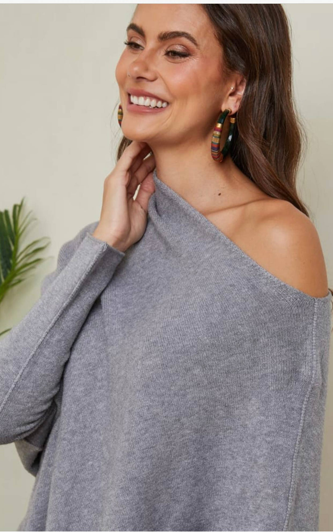 Woman wearing a gray off-shoulder sweater with a neutral background