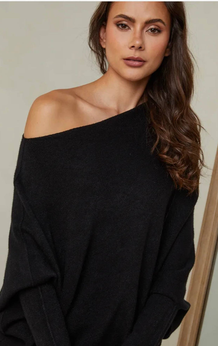 Woman wearing a black off-shoulder top against a neutral background