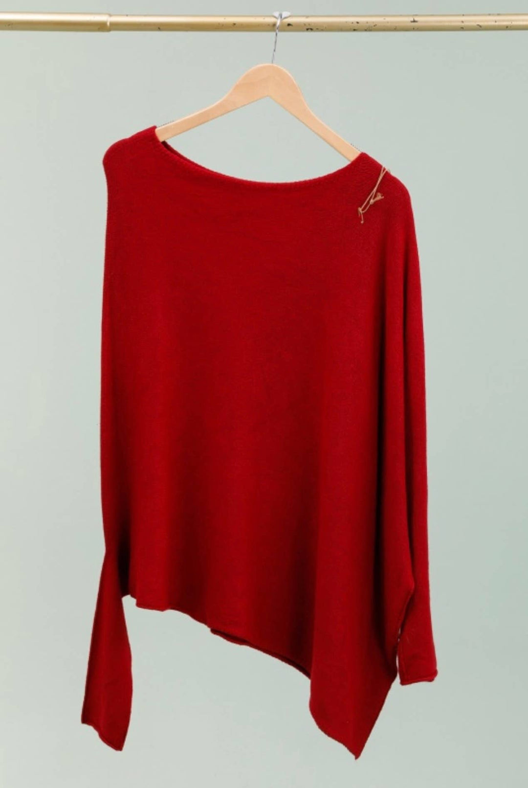 Red sweater on a hanger against a light gray background