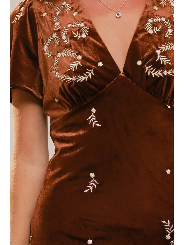 Brown velvet dress with white floral embroidery on a plain background