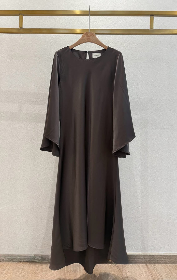 Brown dress hanging on a wooden hanger against a light gray wall.