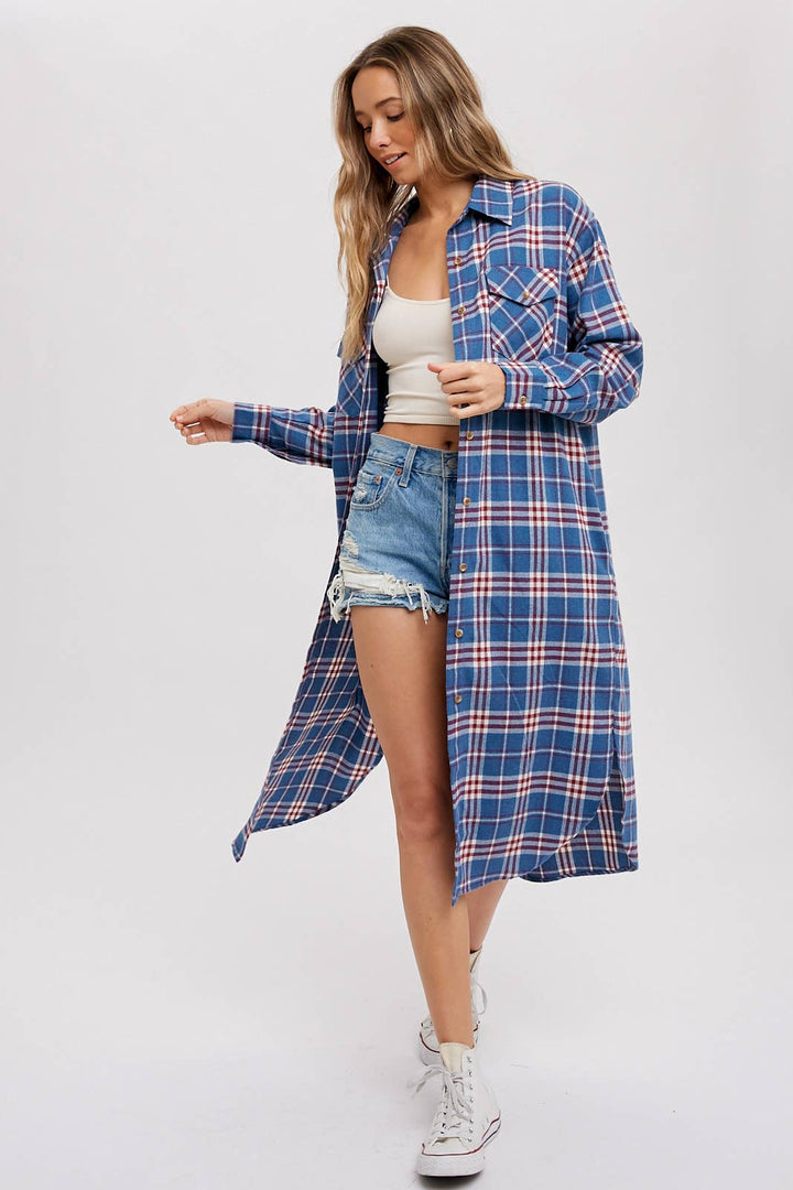 Woman wearing a blue plaid shirt over a white crop top and denim shorts on a white background