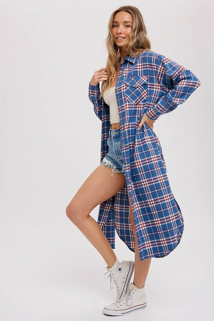 Woman wearing a blue plaid shirt dress with white sneakers on a plain background