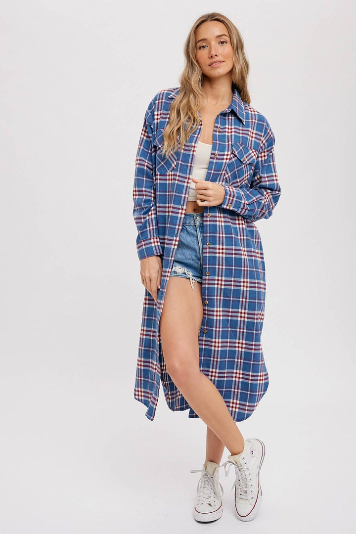Woman wearing a blue plaid shirt over a white top and denim shorts on a white background