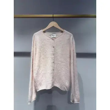 A light pink textured cardigan sweater with a round neckline and button-front closure, hanging on a wooden hanger against a dark gray wall.