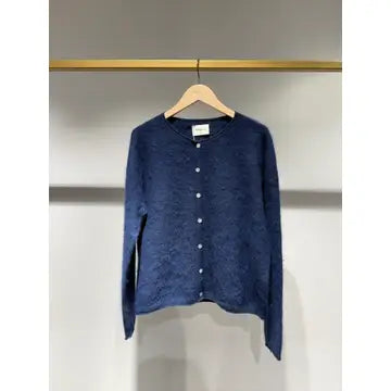 A textured navy blue cardigan sweater with a button-up front, hanging on a wooden hanger from a gold clothing rack against a neutral gray wall.