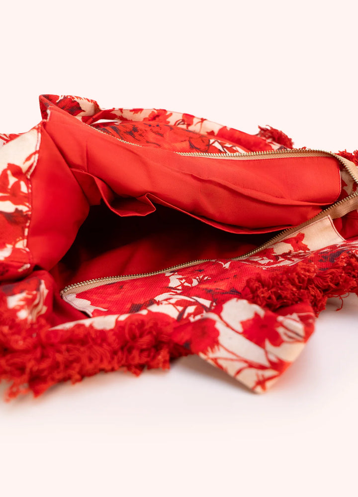 Red floral-patterned bag with a gold zipper on a white background