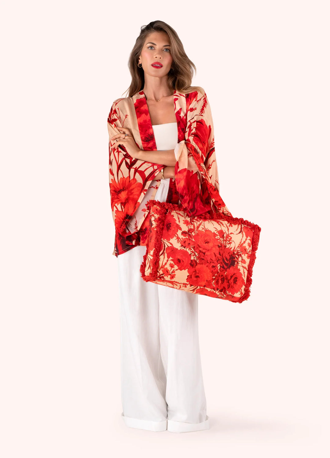 Woman wearing a red and beige floral kimono over a white outfit on a white background
