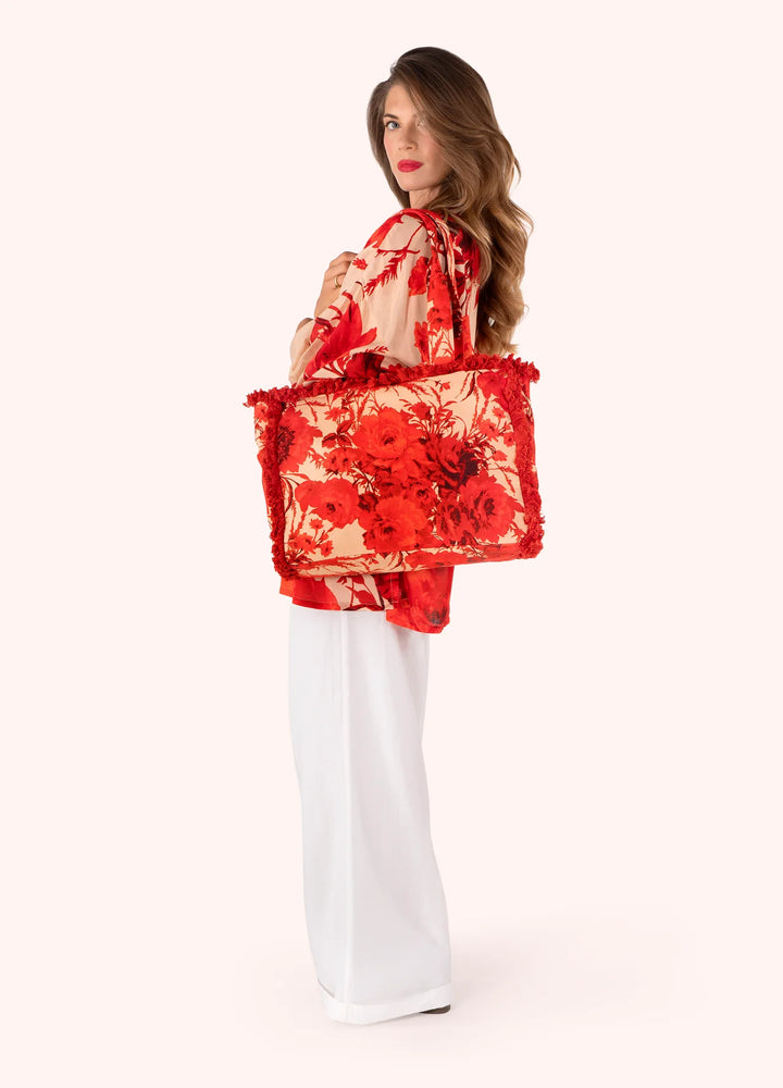 Woman holding a red floral bag against a white background