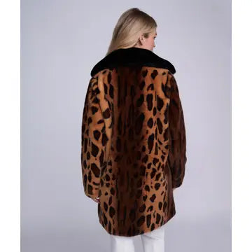 A woman viewed from the back wearing a brown leopard-print faux fur coat with a black collar, set against a plain light gray studio background.