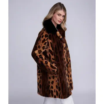 A woman modeling a brown and black leopard-print faux fur coat with a dark collar, set against a plain light gray studio background.