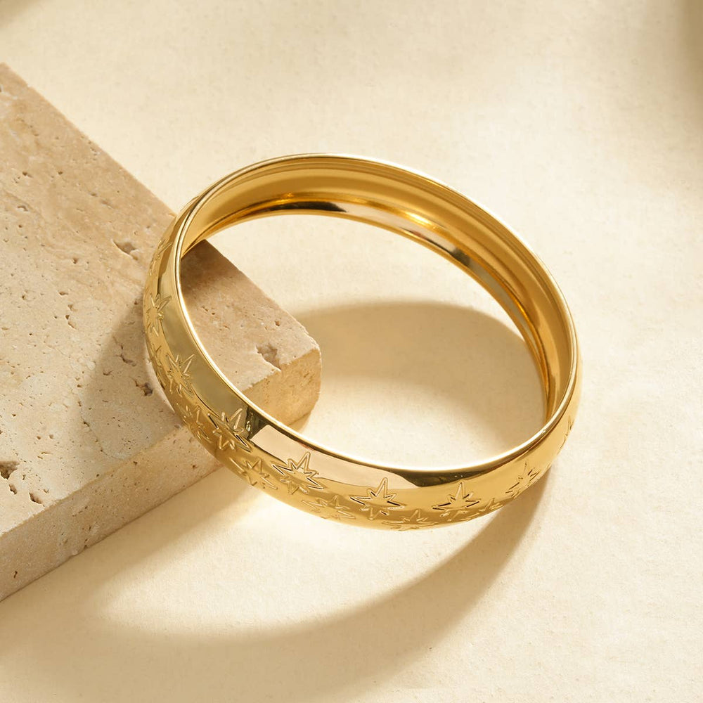 Gold ring with intricate design on a beige stone surface