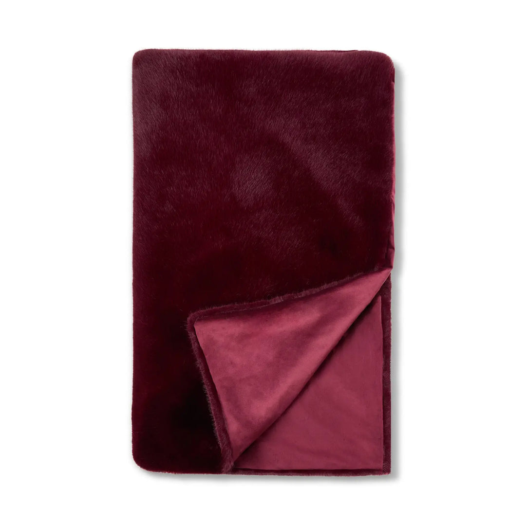 A folded plush throw blanket in a deep burgundy color, shown on a clean white background with one corner folded over to reveal the soft texture of both sides.
