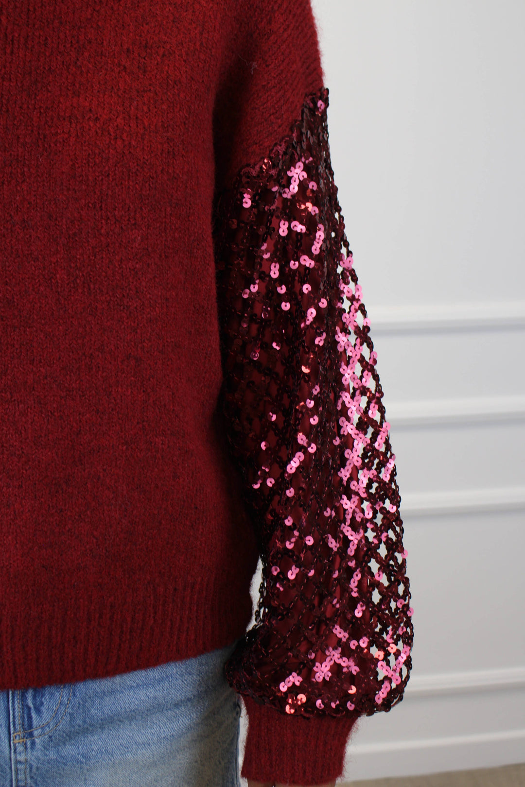 Red sweater with pink sequin sleeves on a white background