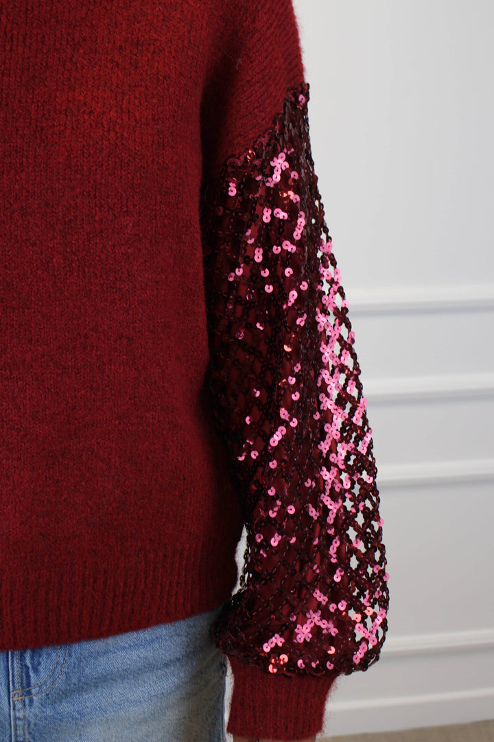 Red sweater with pink sequin sleeves on a white background