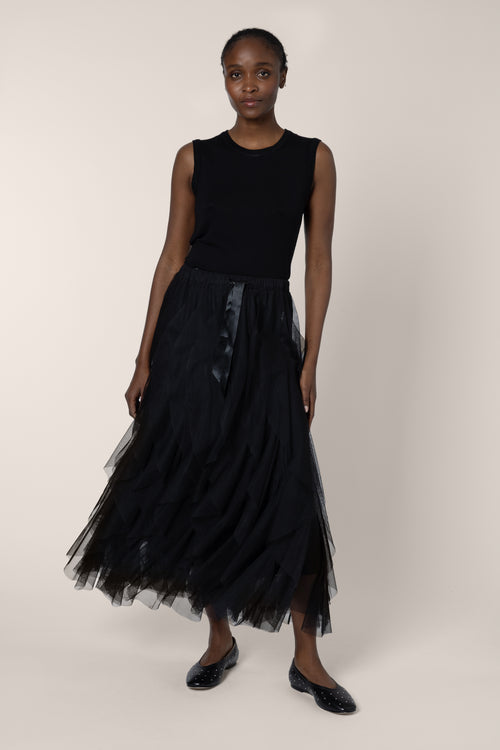Woman wearing a black sleeveless top and tulle skirt on a white background