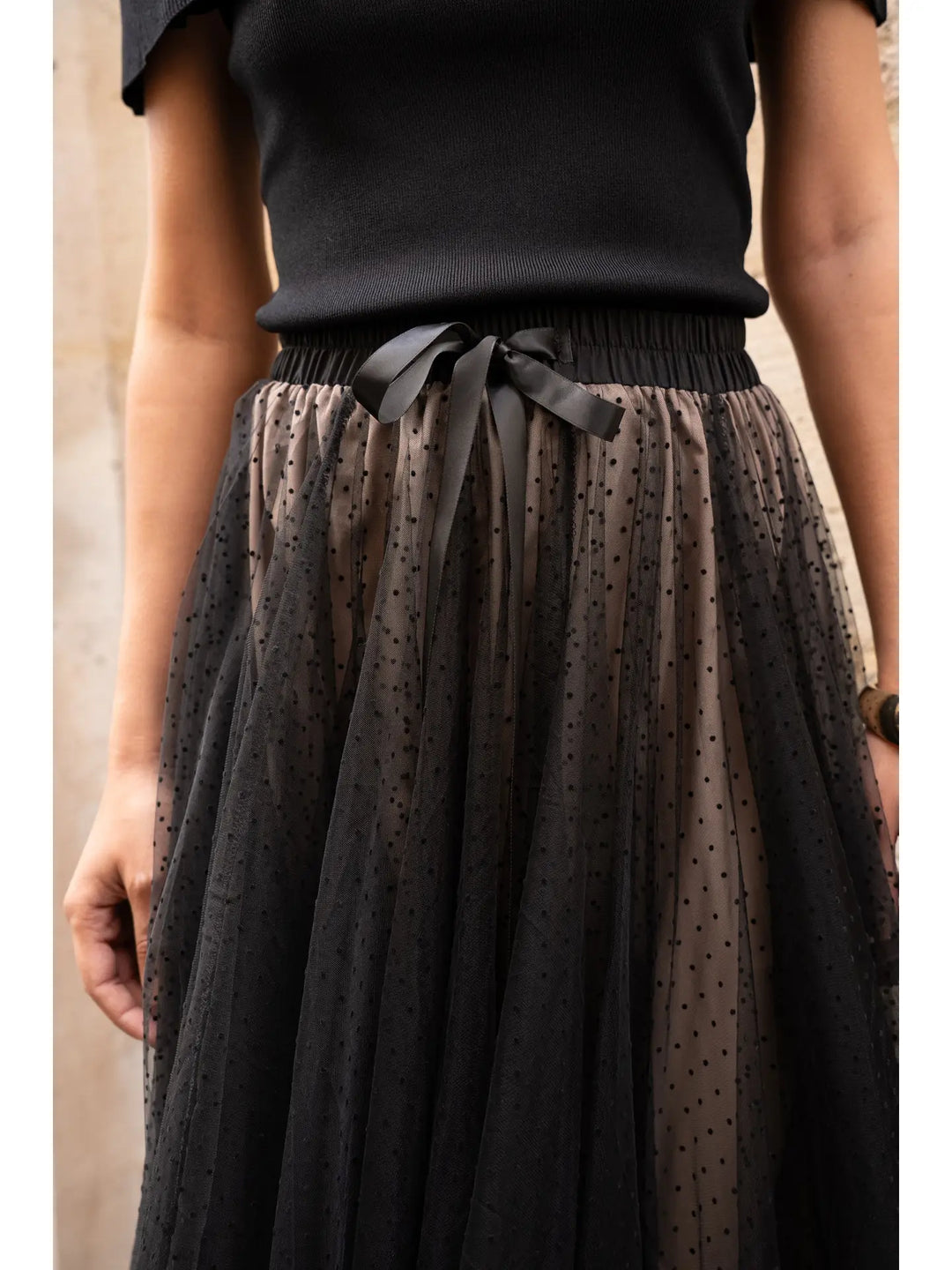 Black tulle skirt with a bow detail worn by a person against a neutral background