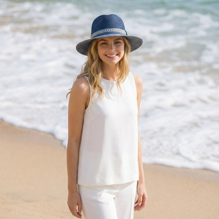 Woman wearing a white sleeveless top and blue hat on a beach