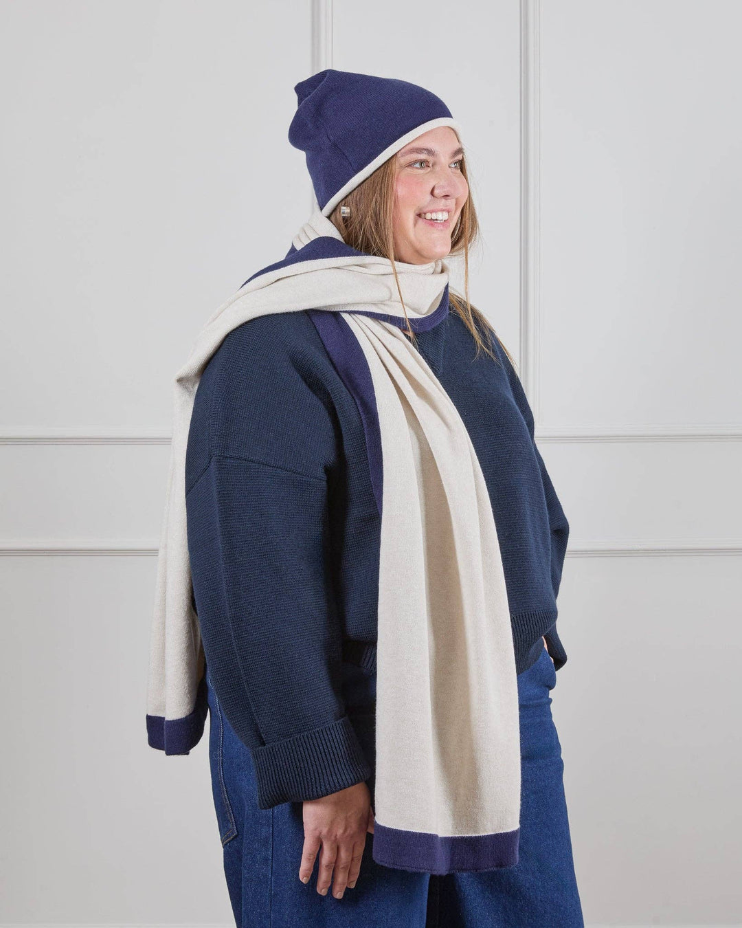 Person wearing a navy blue outfit with a white scarf against a white background