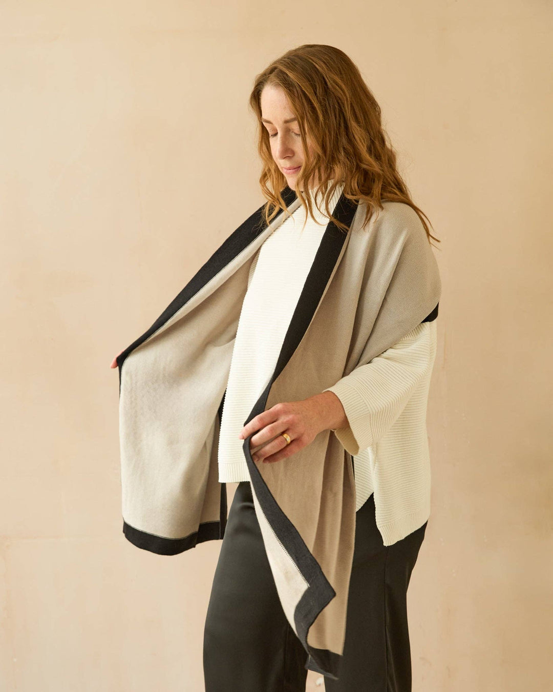 Woman wearing a beige and black kimono-style garment against a beige background